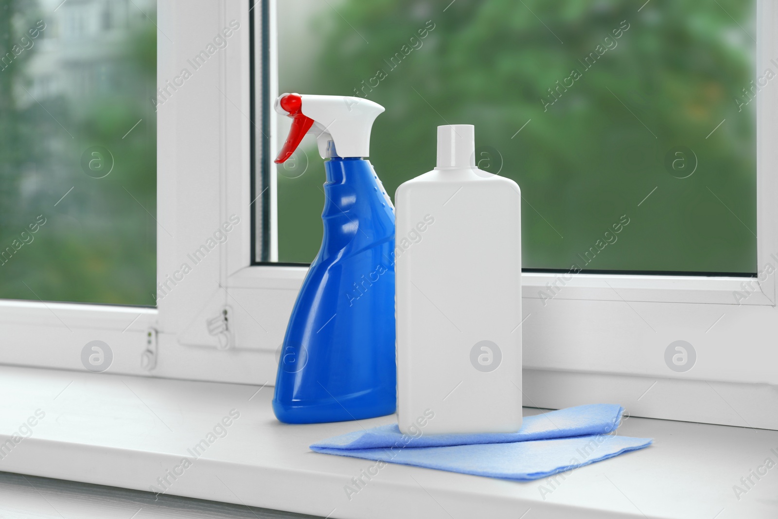 Photo of Bottles of cleaning products and dustrag on windowsill