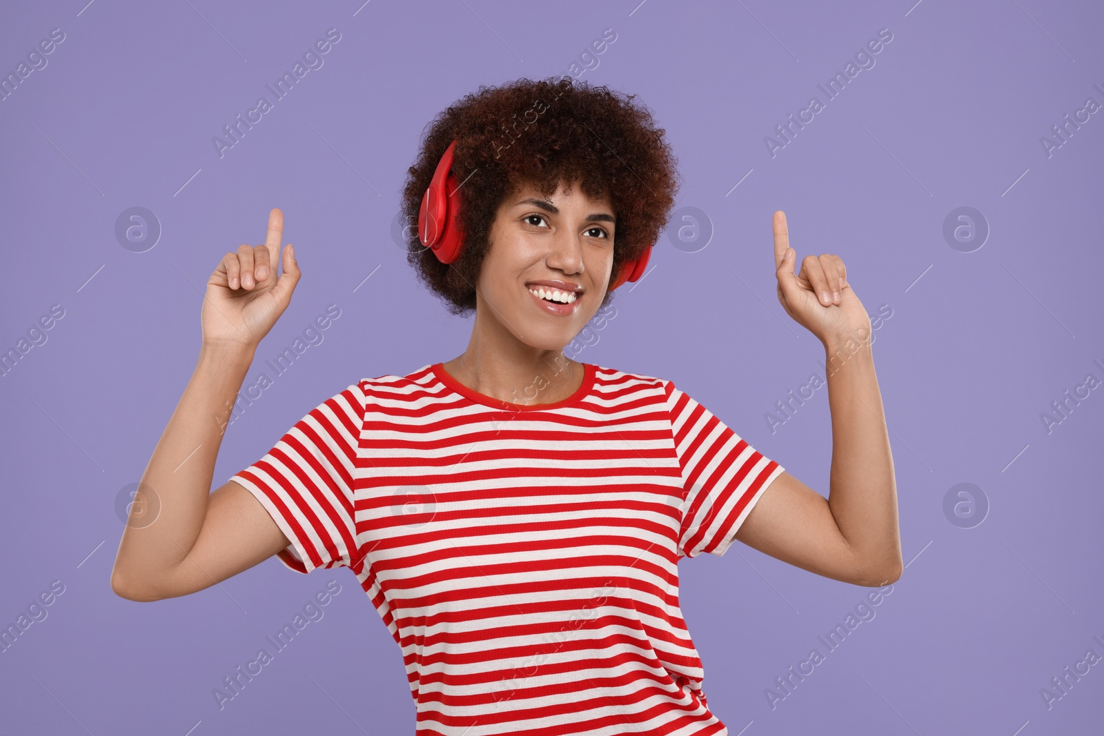 Photo of Happy young woman in headphones enjoying music on purple background