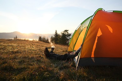 Photo of Man inside camping tent in mountains at sunset