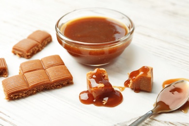 Delicious candies with caramel sauce on table