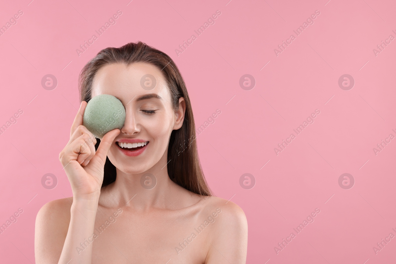 Photo of Happy young woman holding face sponge on pink background. Space for text