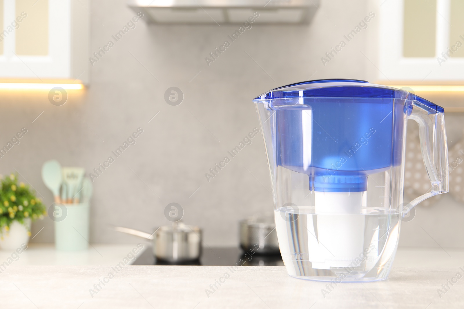 Photo of Water filter jug on light grey table in kitchen, space for text