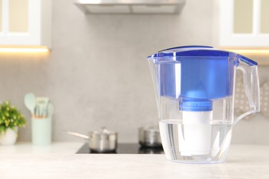 Water filter jug on light grey table in kitchen, space for text