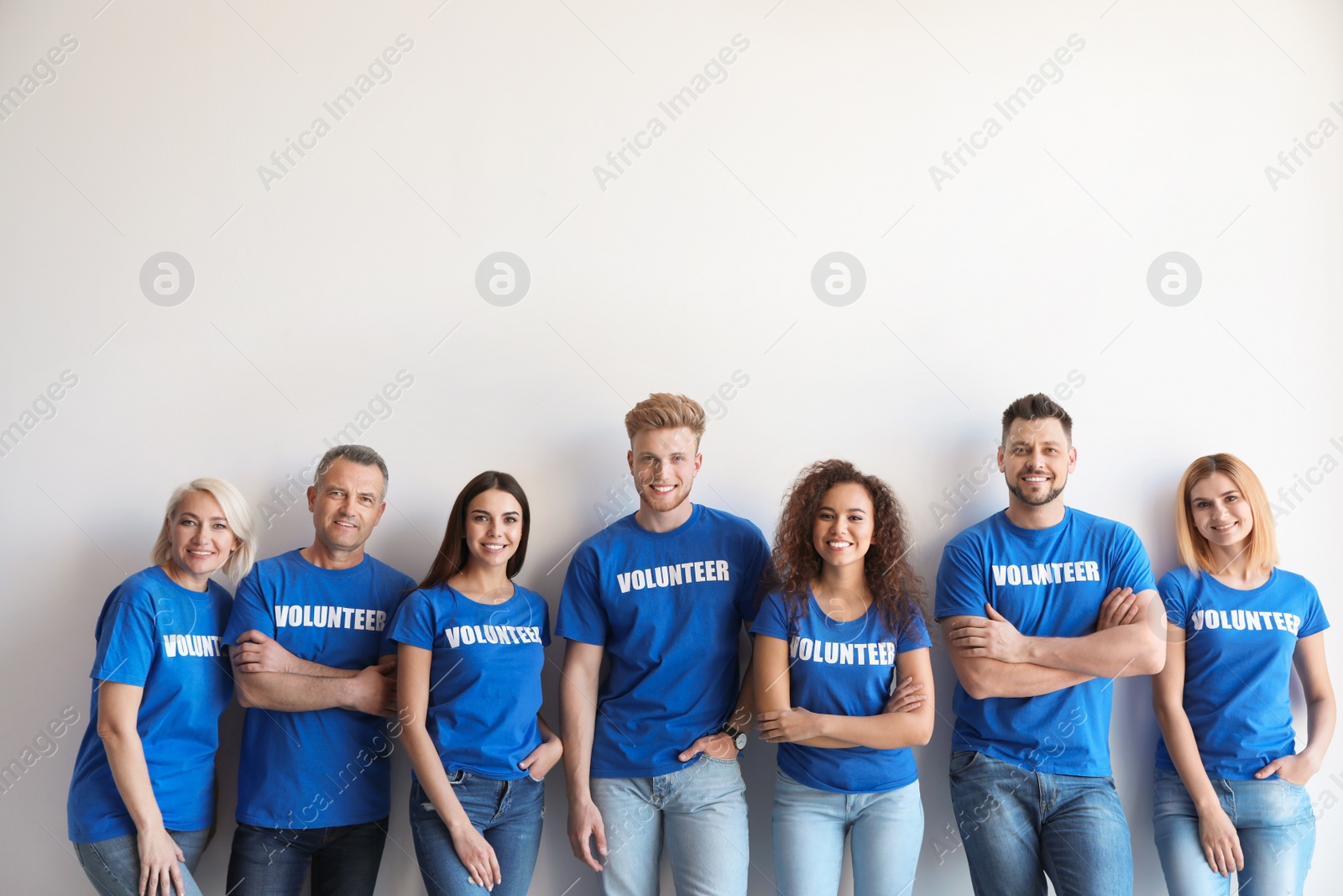 Photo of Team of volunteers in uniform on light background