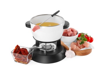 Photo of Fondue pot with oil, fork, raw meat pieces and other products isolated on white