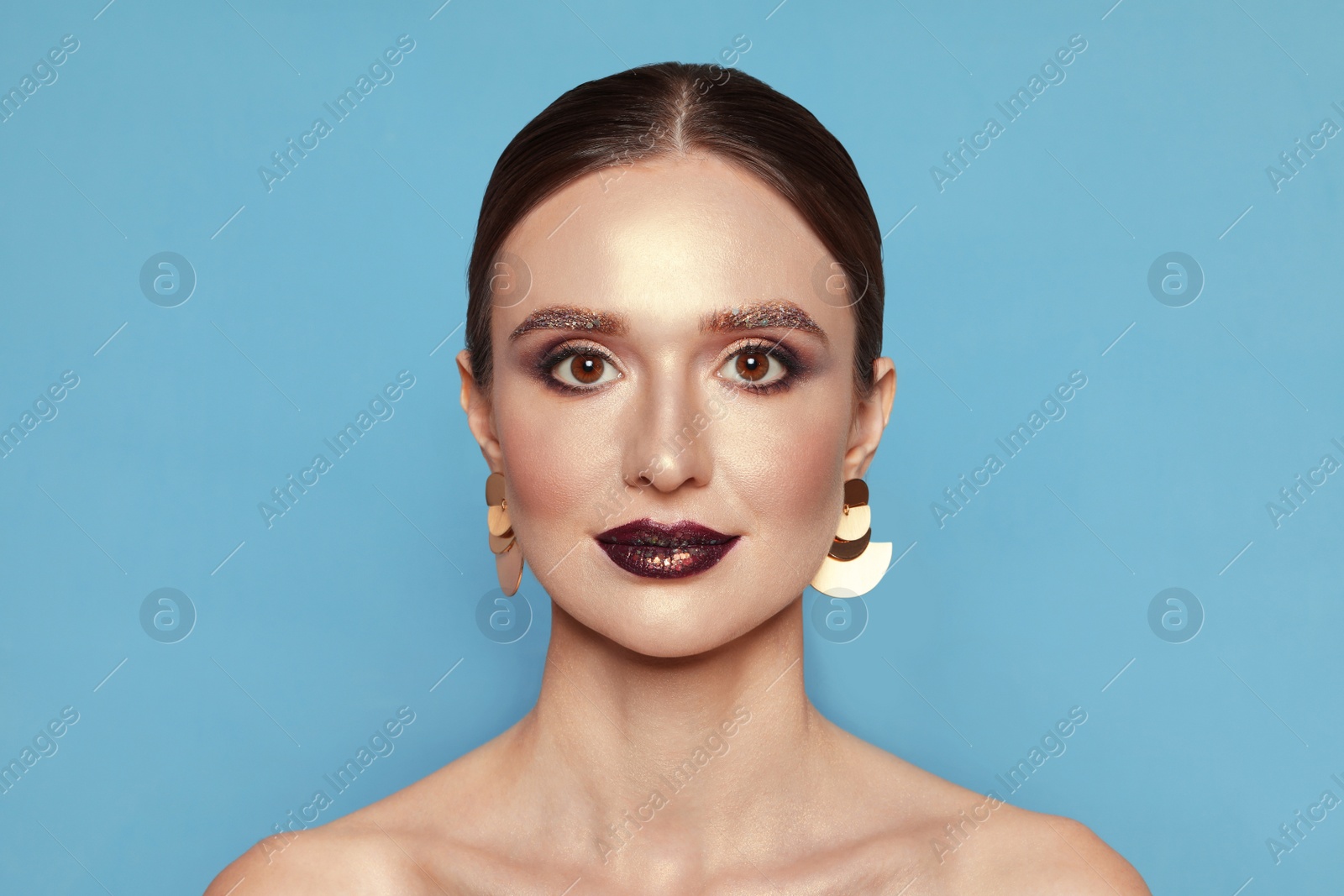 Photo of Beautiful young woman with glitter makeup on blue background