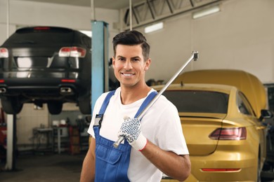 Photo of Portrait of professional mechanic with tire wrench at automobile repair shop