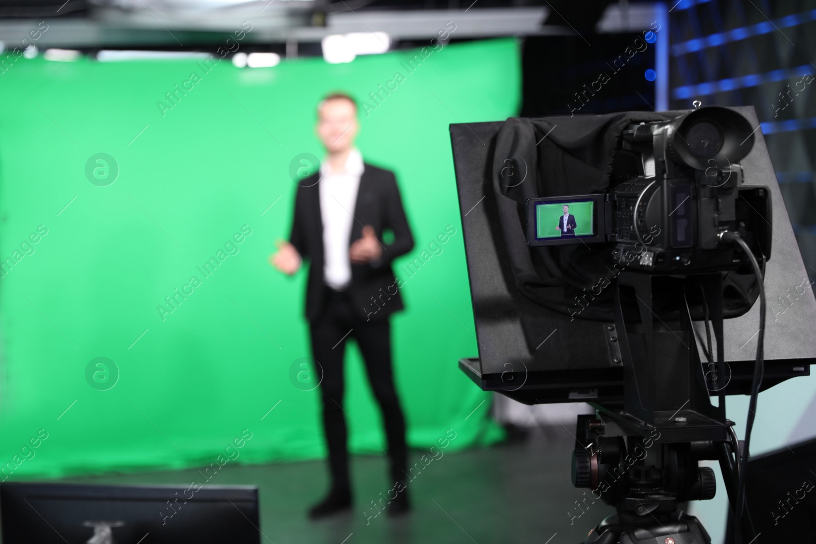 Photo of Presenter working in studio, focus on video camera