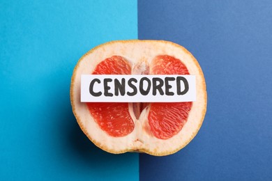 Photo of Card with word Censored and half of grapefruit on color background, top view