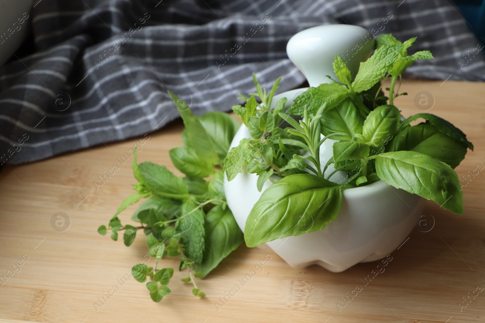 Photo of Mortar with different fresh herbs on wooden table, closeup. Space for text