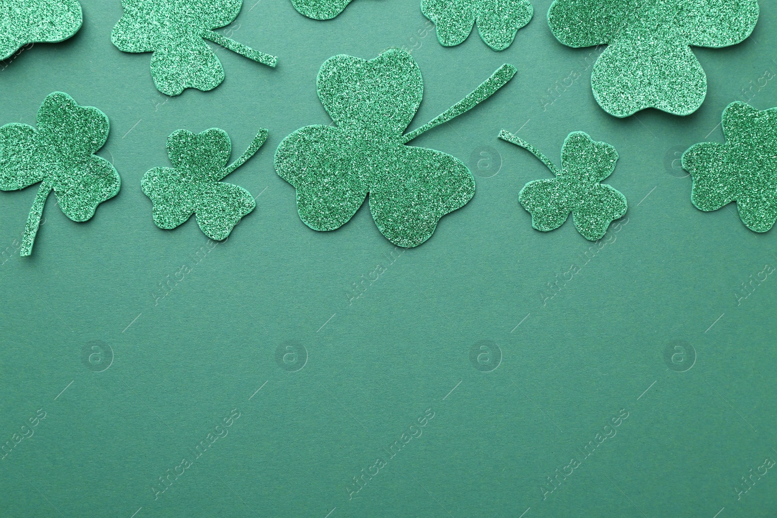 Photo of St. Patrick's day. Decorative clover leaves on green background, flat lay. Space for text