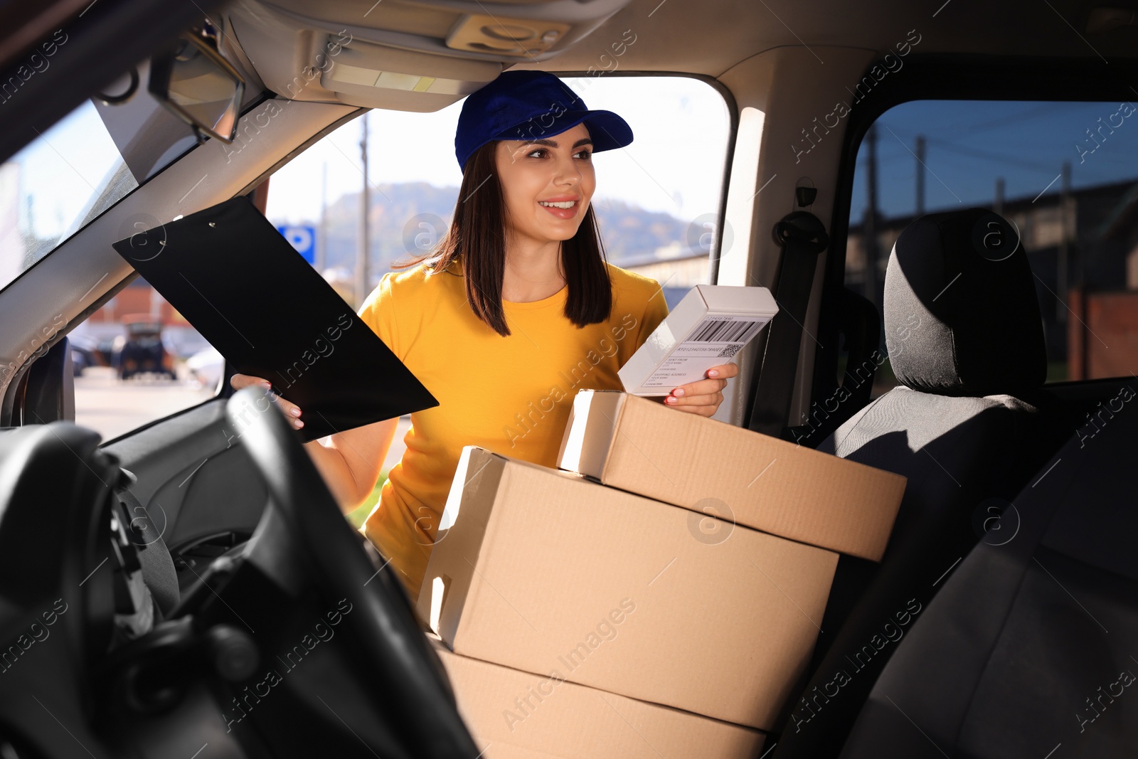 Photo of Courier with clipboard checking packages in car