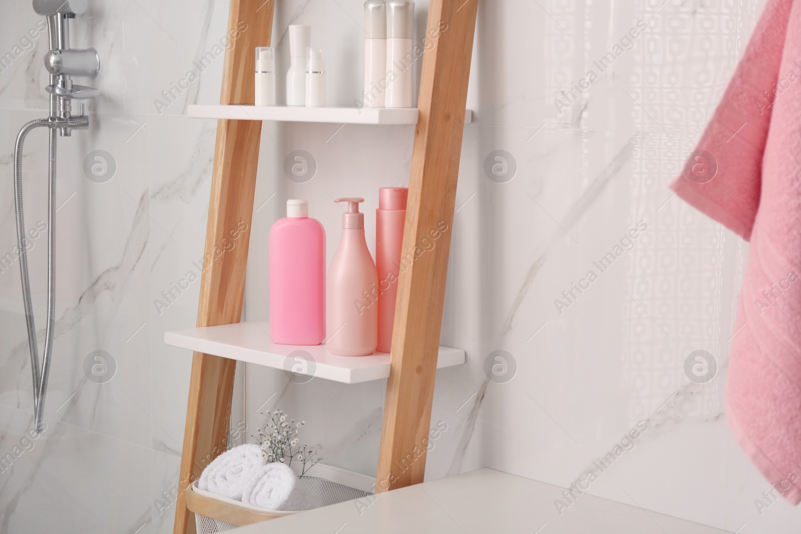 Photo of Soft towels and different toiletries on decorative ladder in bathroom. Interior design