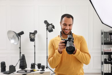 Photo of Young professional photographer with camera in modern photo studio, space for text