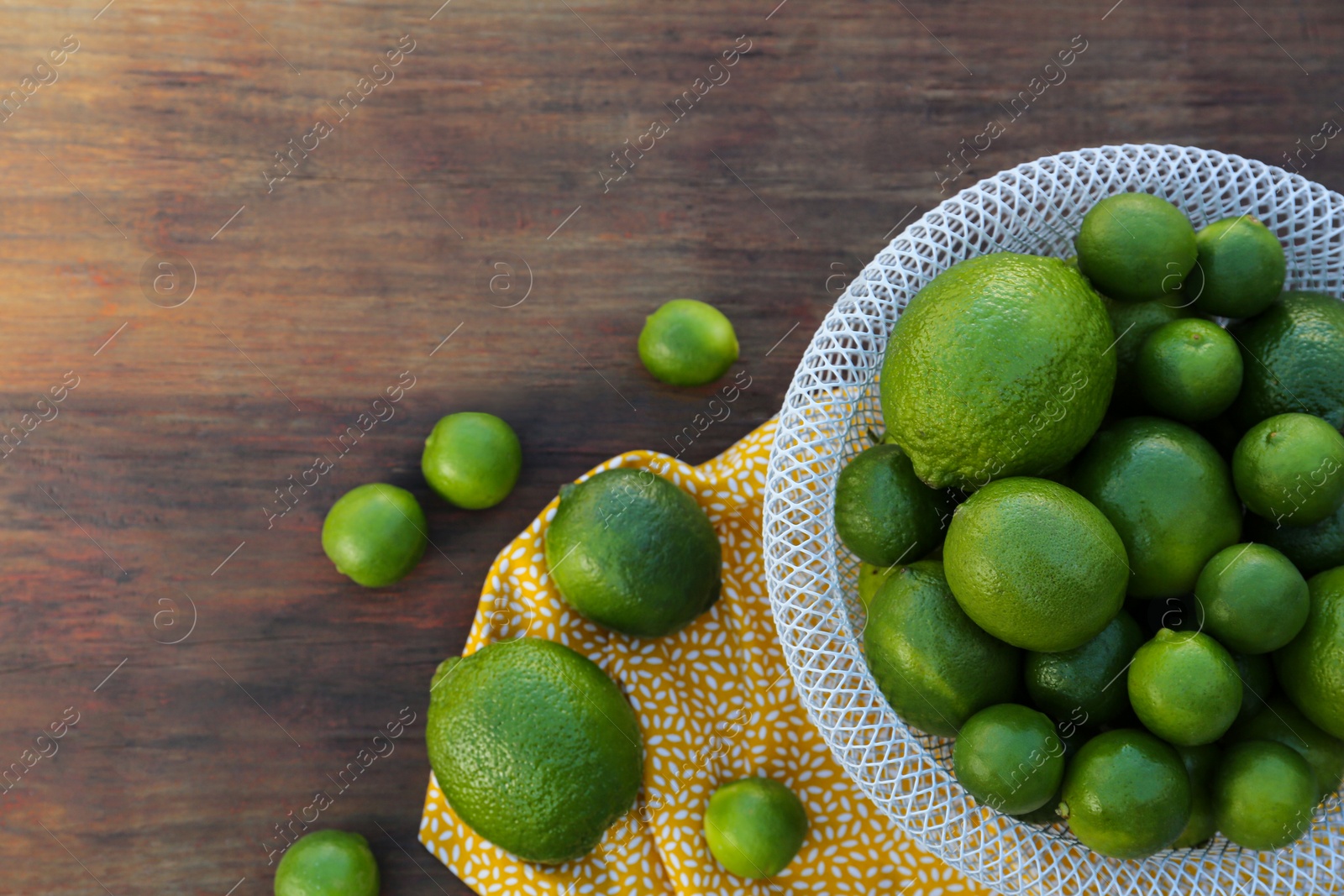 Photo of Fresh ripe limes on wooden table, flat lay. Space for text