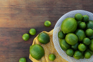 Fresh ripe limes on wooden table, flat lay. Space for text