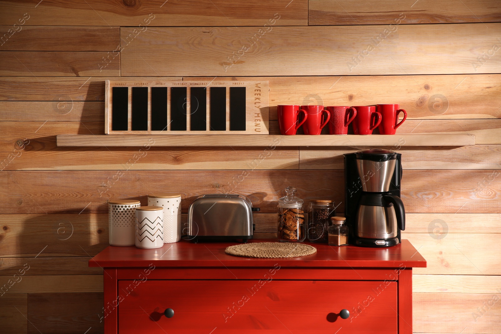 Photo of Stylish room interior with modern coffeemaker and toaster on red chest of drawers