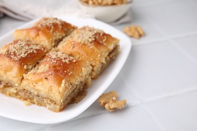 Photo of Eastern sweets. Pieces of tasty baklava on white tiled table, closeup. Space for text