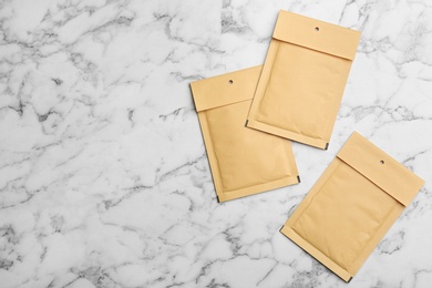 Photo of Kraft paper envelopes on white marble background, flat lay. Space for text