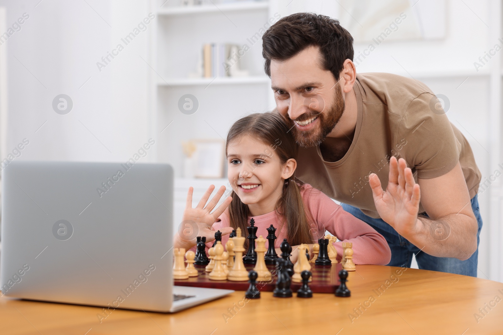 Photo of Father teaching his daughter to play chess following online lesson at home