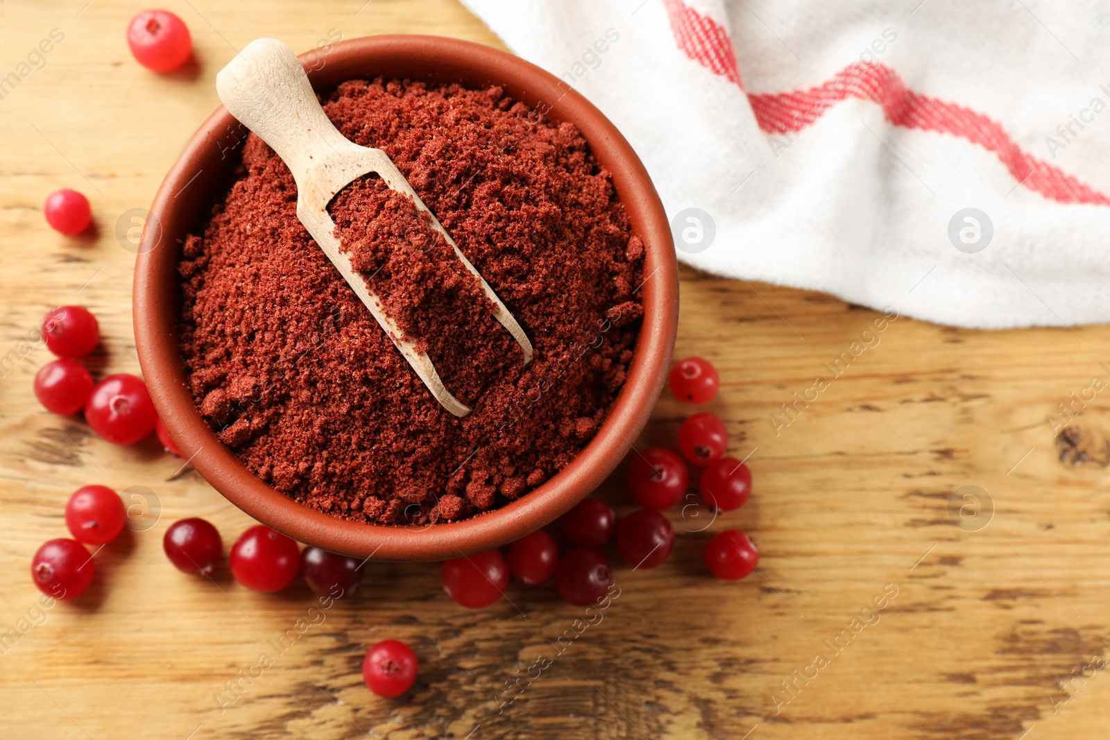 Photo of Cranberry powder in bowl, scoop and fresh berries on wooden table, top view. Space for text