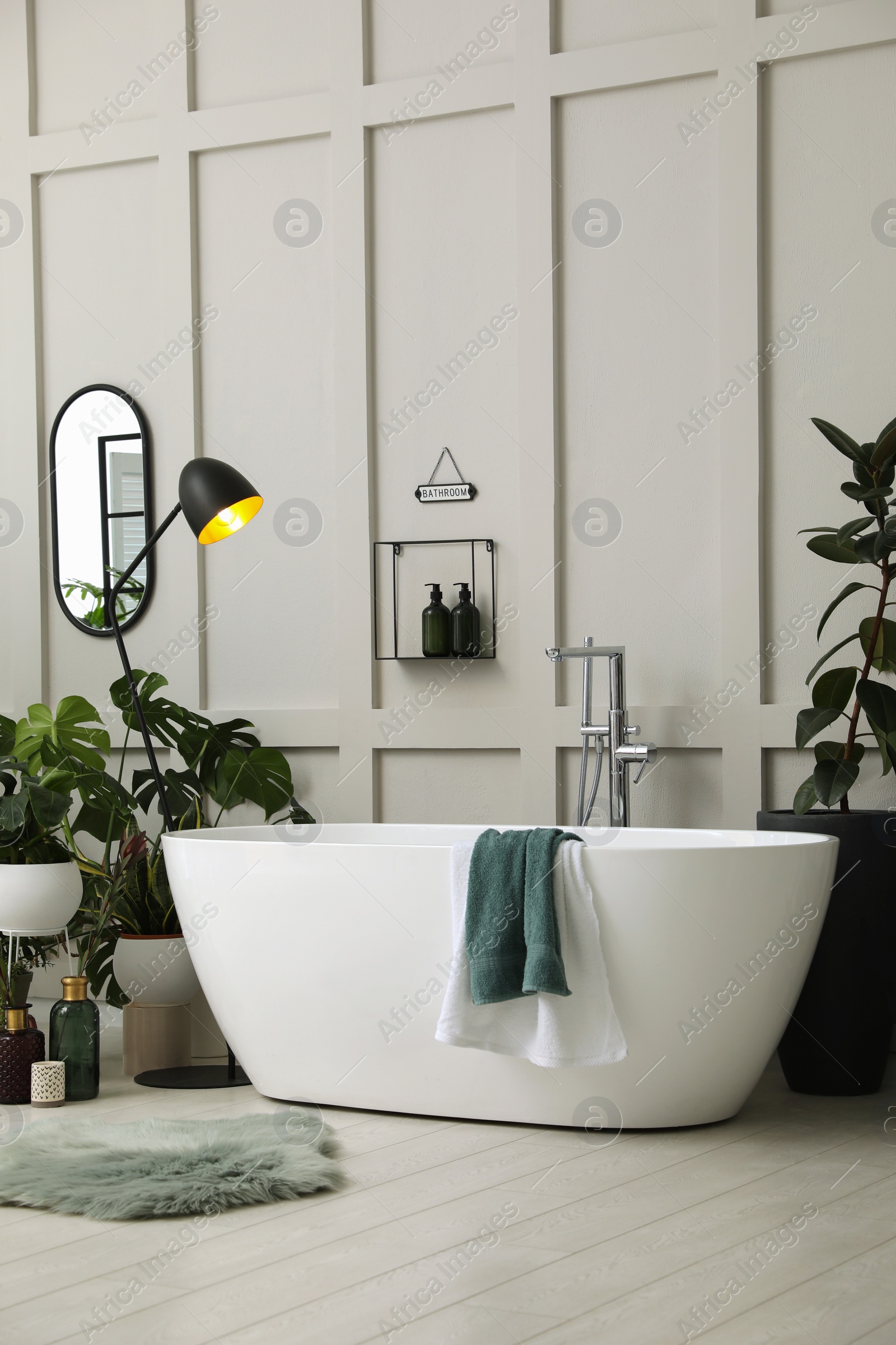 Photo of Stylish bathroom interior with modern tub and beautiful houseplants. Home design