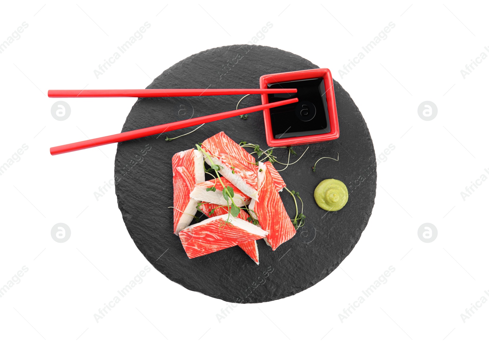 Photo of Slate plate with fresh crab sticks and soy sauce on white background, top view