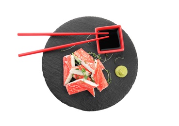 Photo of Slate plate with fresh crab sticks and soy sauce on white background, top view
