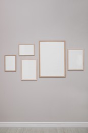 Photo of Empty frames on grey wall indoors. Mockup for design