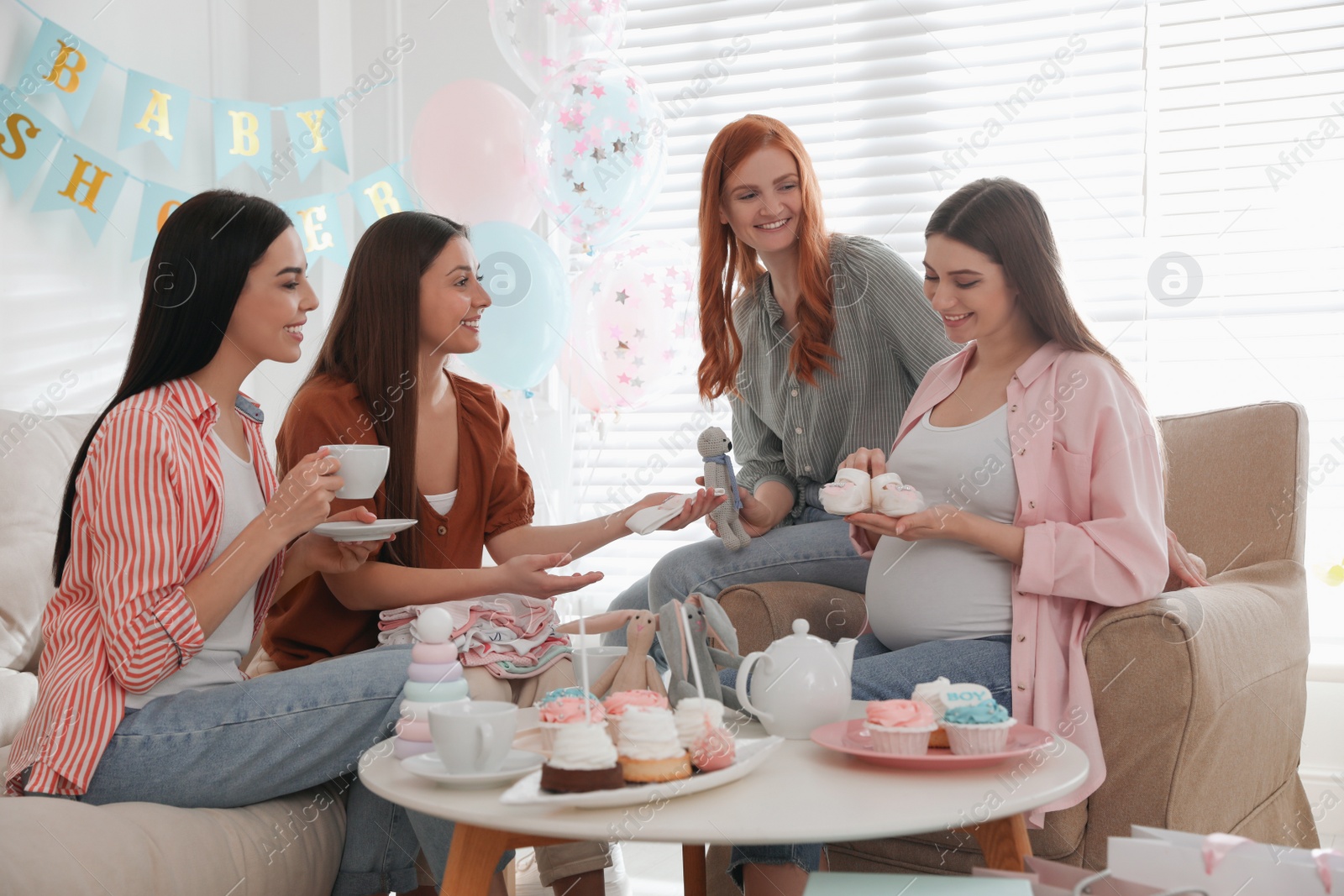 Photo of Happy pregnant woman spending time with friends at baby shower party