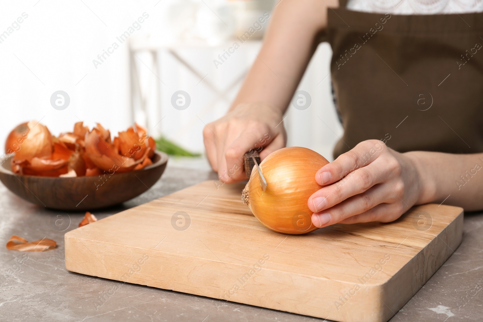 Photo of Woman cutting onion on wooden board, closeup