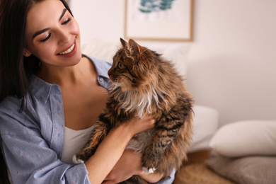 Beautiful young woman with her cute cat in bedroom. Fluffy pet