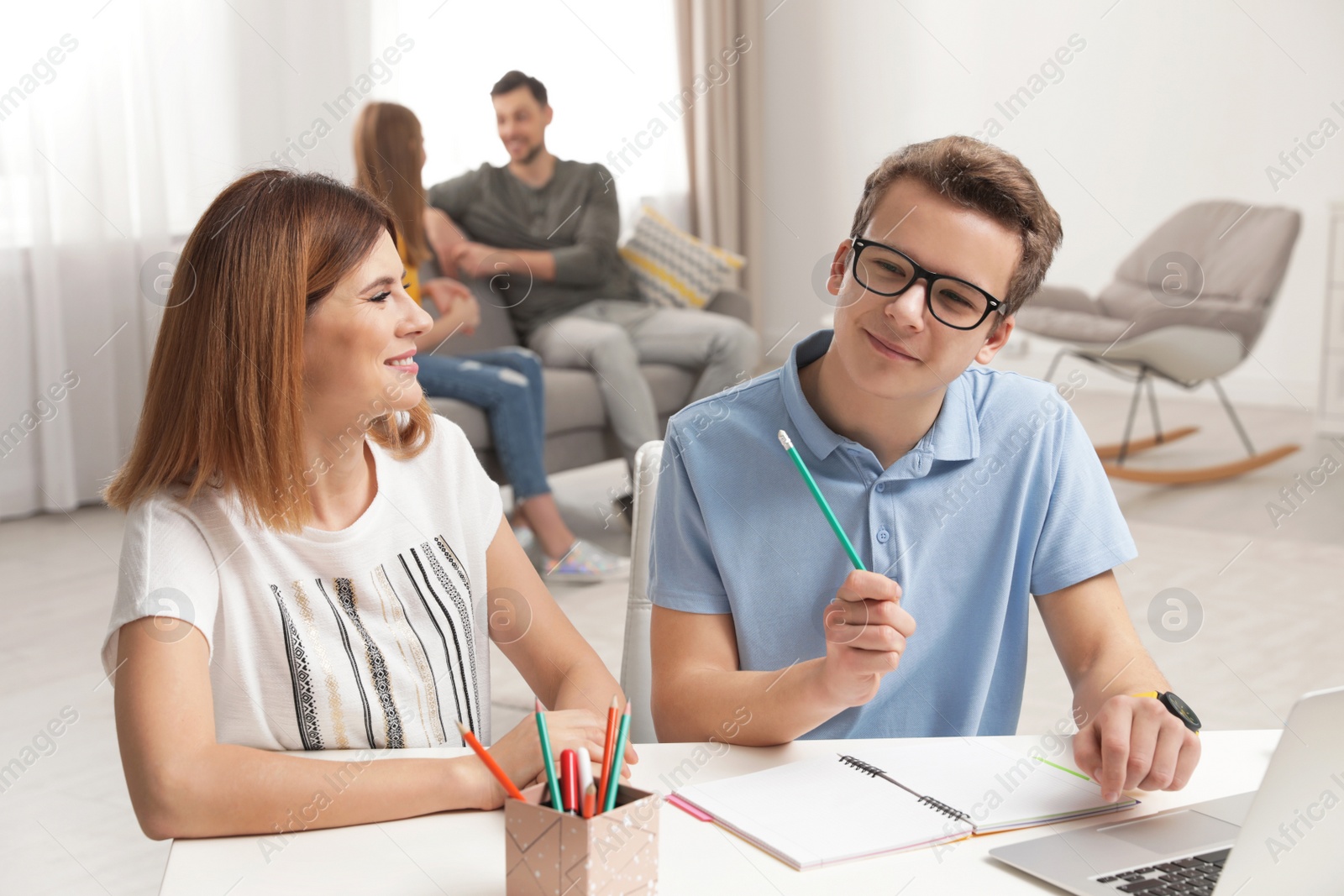 Photo of Mother helping her teenager son with homework indoors