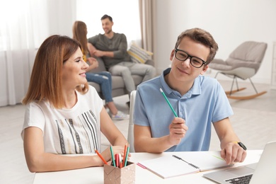 Mother helping her teenager son with homework indoors