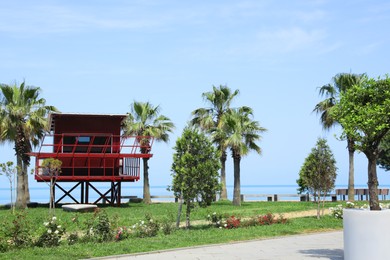 Photo of Red wooden lifeguard house and palm trees on seacoast