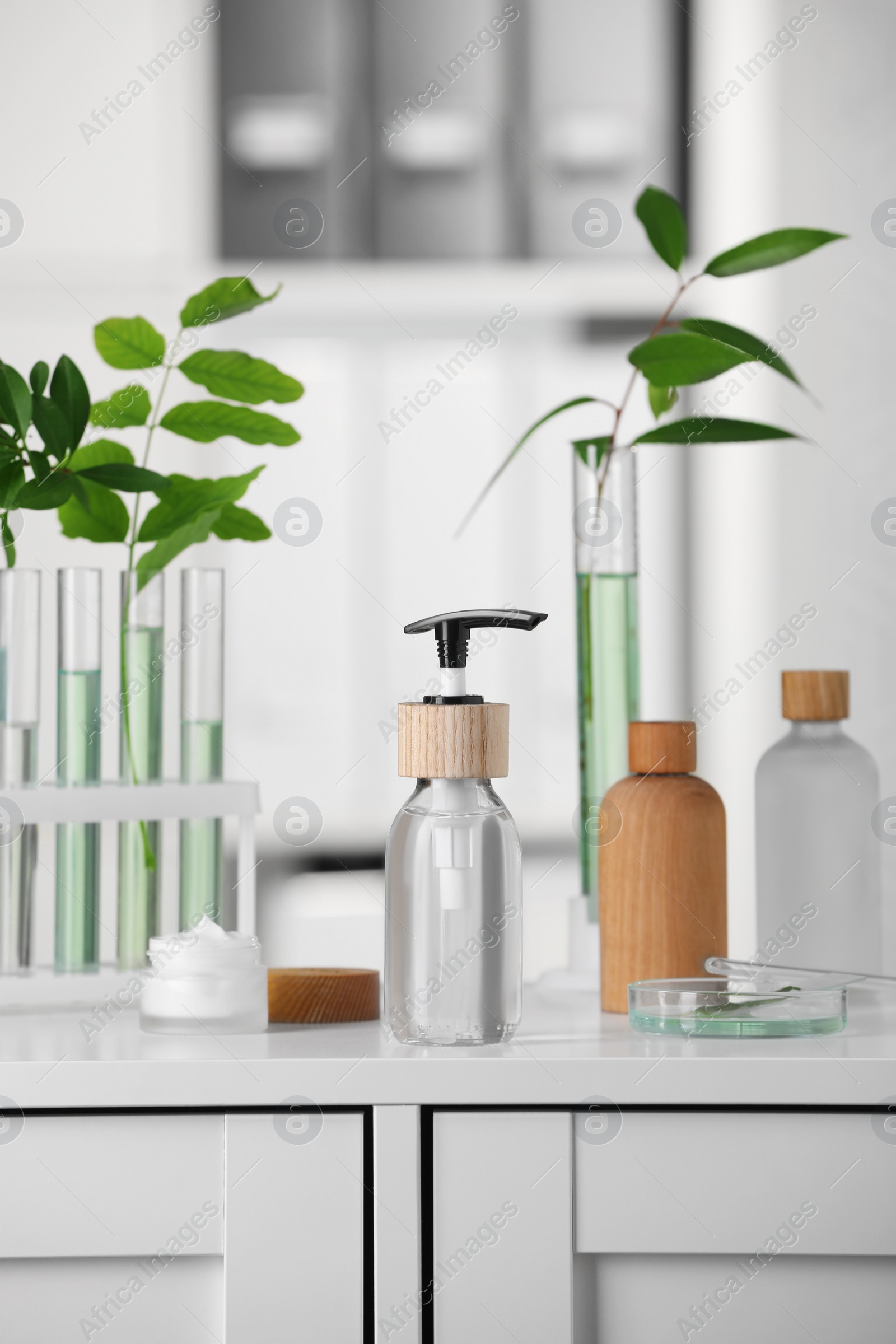 Photo of Bottles and glass tubes with leaves on white lab drawer indoors