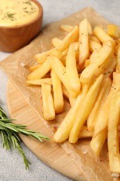 Photo of Delicious french fries served with sauce on grey textured table, closeup