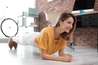 Photo of Beautiful young businesswoman doing exercises in office. Workplace fitness