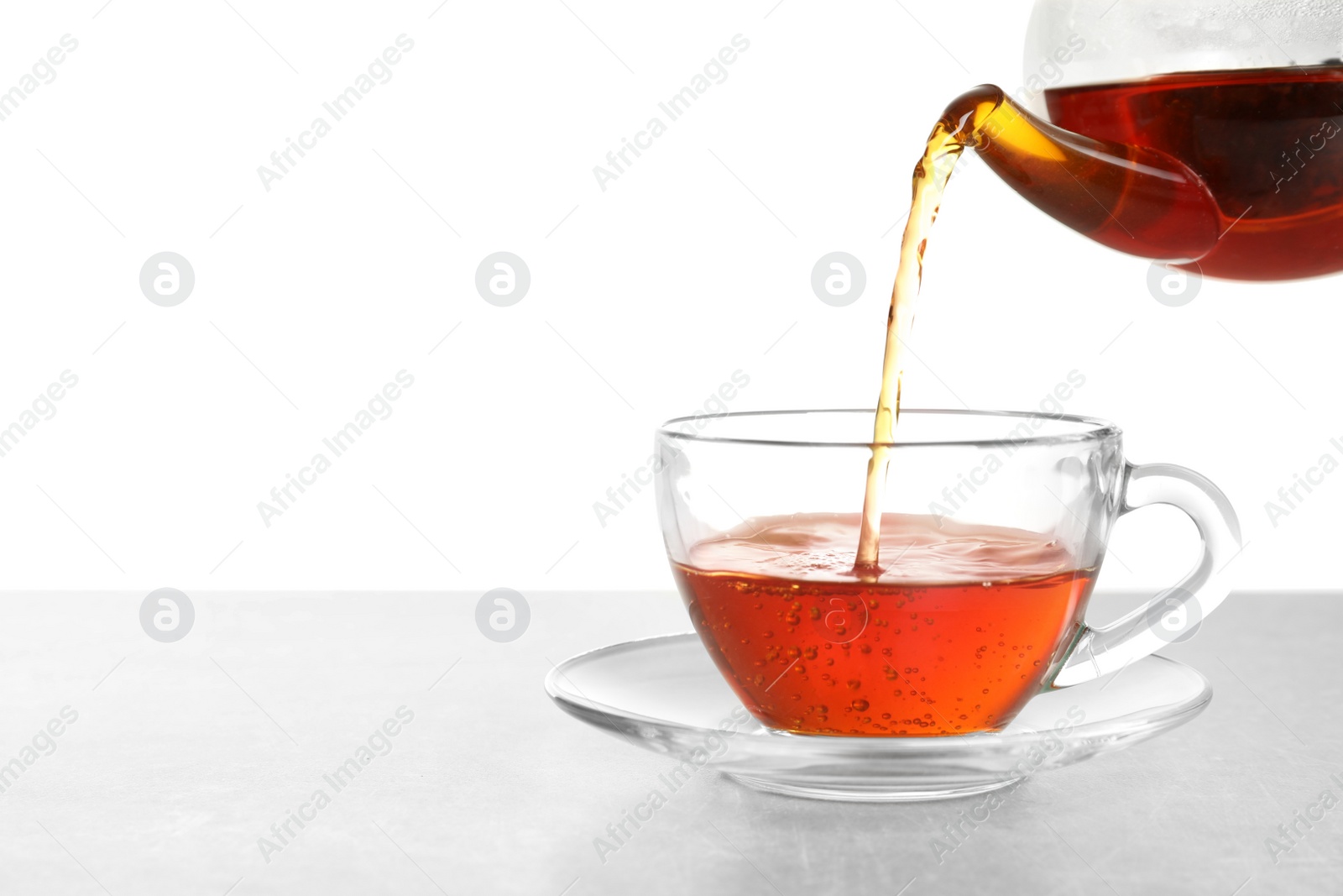 Photo of Pouring hot tea into glass cup on white background