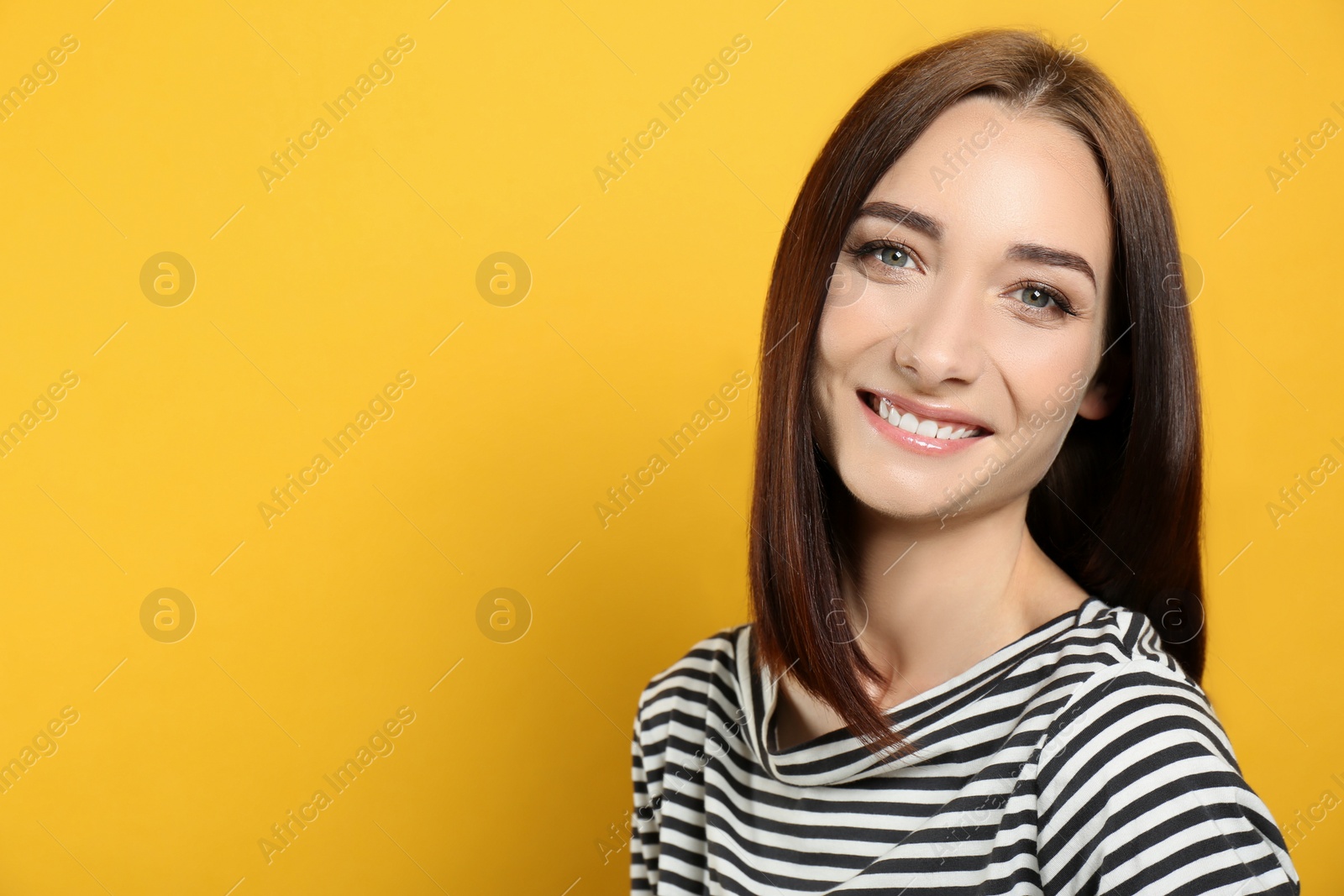 Photo of Portrait of pretty young woman with gorgeous chestnut hair and charming smile on yellow background, space for text