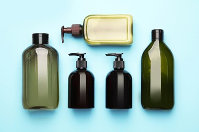 Photo of Bottles of shampoo on light blue background, flat lay