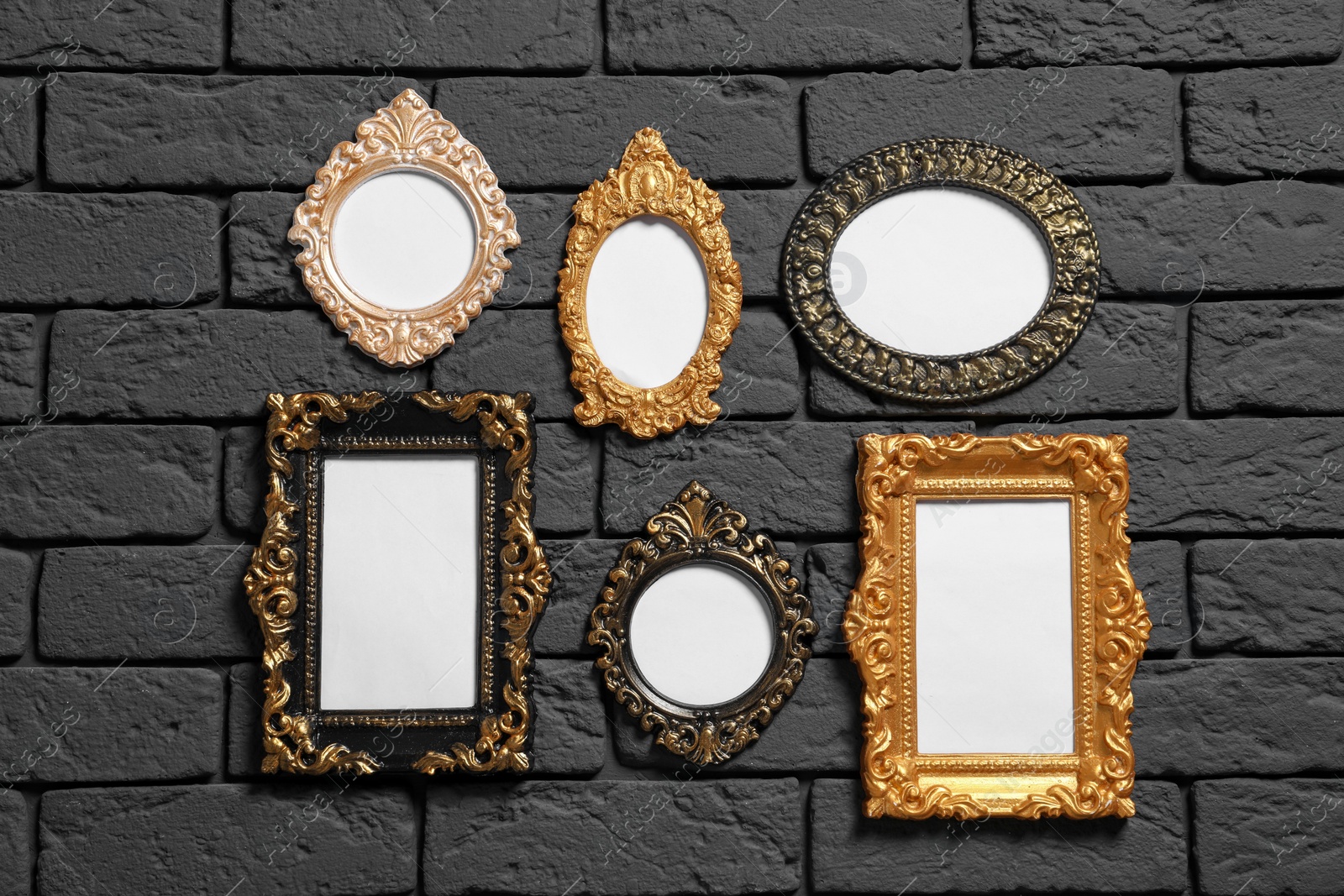 Photo of Empty vintage frames hanging on dark brick wall. Mockup for design