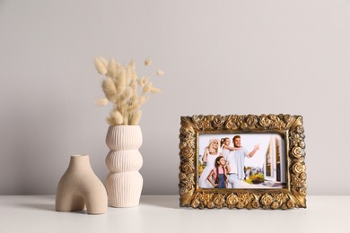 Photo of Vintage square frame with family photo and other decor elements on white table