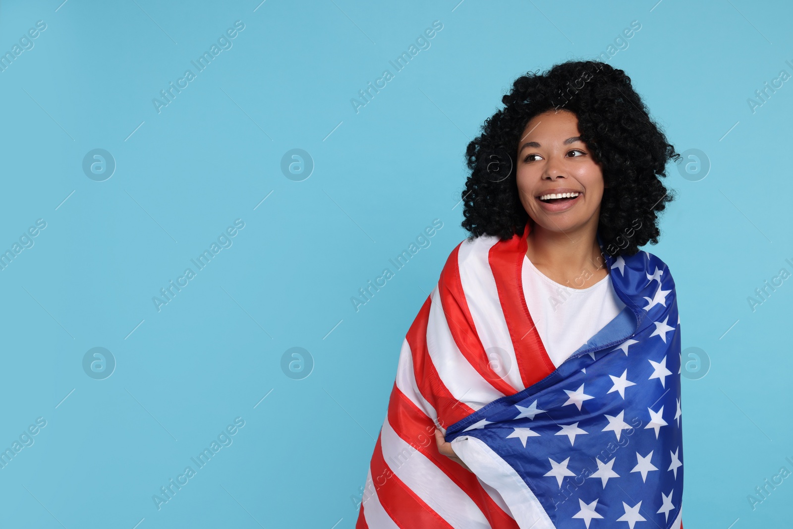 Photo of 4th of July - Independence Day of USA. Happy woman with American flag on light blue background, space for text