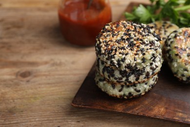 Photo of Delicious vegan cutlets with sesame on wooden table, closeup. Space for text