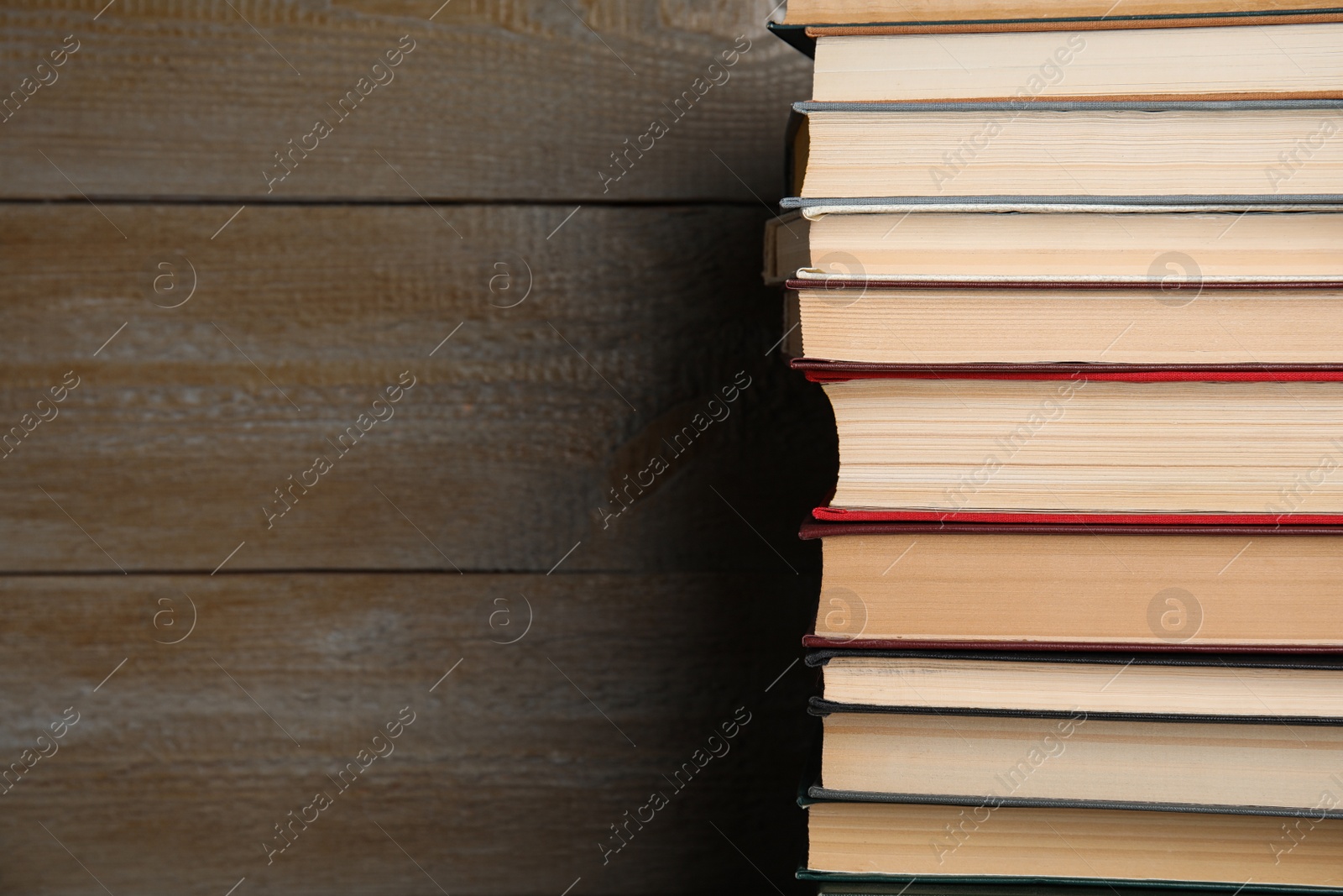 Photo of Stack of hardcover books on wooden background. Space for text