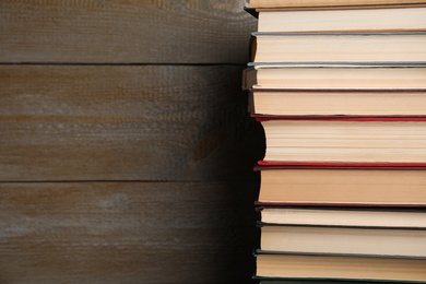 Stack of hardcover books on wooden background. Space for text