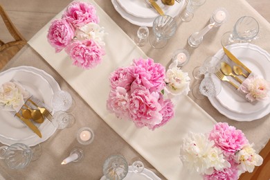 Photo of Stylish table setting with beautiful peonies and burning candles, flat lay