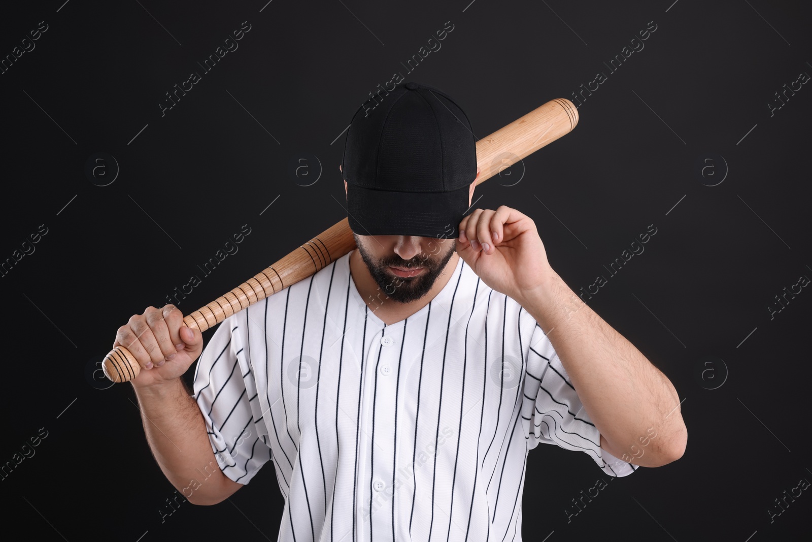 Photo of Man in stylish baseball cap holding bat on black background