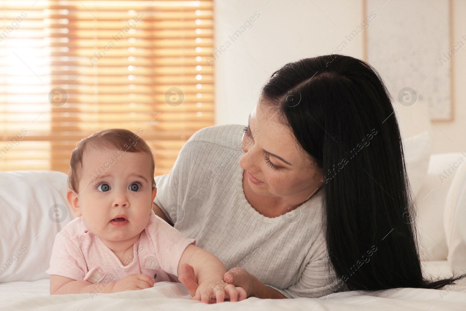 Photo of Happy woman with her little baby on bed at home